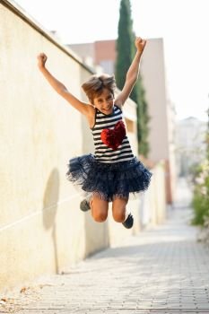 Little girl, eight years old, jumping in an urban park.. Little girl, eight years old, jumping outdoors.