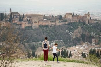 Mother and little daughter looking at the Alhambra of Granada from Cerro de San Miguel. Single parent family doing tourism.. Mother and little daughter looking at the Alhambra