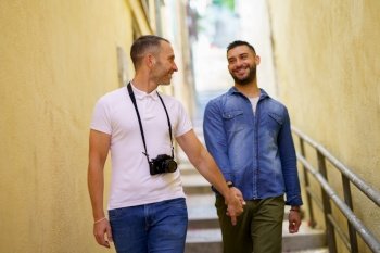 Gay couple tourists walking hand in hand on the street. Homosexual relationship concept.. Gay couple tourists walking hand in hand on the street.