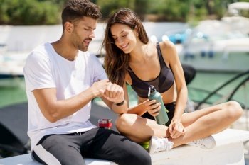 Man showing his marks to an athletic woman on a sports watch after exercise. People using smartwatch.. Man showing his marks to a woman on a sports watch after exercise. People using smartwatch.