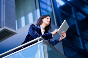 Business woman wearing blue suit using digital tablet in an office building. Lifestyle concept.. Business woman wearing blue suit using digital tablet in an office building.