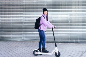 Young woman in her twenties riding an electric scooter. Lifestyle concept.. Young woman in her twenties riding an electric scooter.