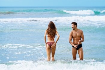 Young couple of beautiful athletic bodies bathing together on the beach enjoying their holiday at sea. Young couple bathing together on the beach enjoying their holiday at sea