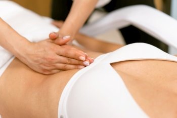 Middle-aged woman having a belly massage in a beauty salon. Body care treatment in a beauty centre.. Middle-aged woman having a belly massage in a beauty salon.