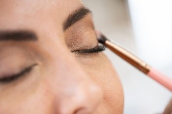 Close-up of a make-up artist applying eye shadow to her client. Beauty and Aesthetic concepts.. Close-up of a make-up artist applying eye shadow to her client.