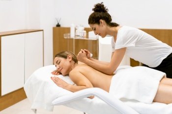 Female masseuse giving a back massage to a woman in a beauty parlour. Body care treatment in a beauty centre.. Female masseuse giving a back massage to a woman in a beauty parlour.