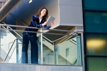 Business woman wearing blue suit using digital tablet in an office building. Lifestyle concept.. Business woman wearing blue suit using digital tablet in an office building.
