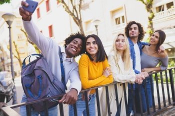 Multi-ethnic group of friends taking a selfie in the street with a smartphone. Young people having fun together.. Multi-ethnic group of friends taking a selfie in the street with a smartphone.