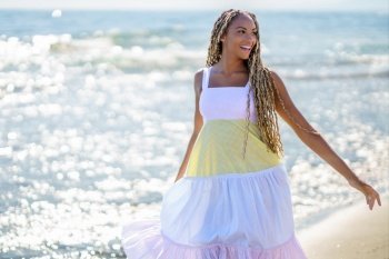 Black female walking along the shore of the beach wearing a beautiful long dress. Young girl enjoying her vacations.. Black female walking along the shore of the beach wearing a beautiful long dress.