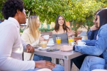 Multi-ethnic group of friends having a drink together in an outdoor bar. Young people having fun.. Multi-ethnic group of friends having a drink together in an outdoor bar.