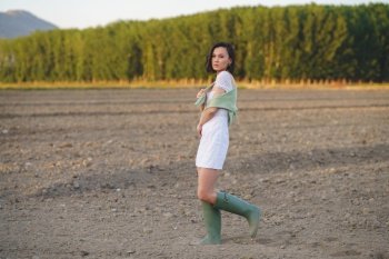 Pretty young Asian woman, walking in the countryside, wearing a white dress and green wellies.. Asian woman, walking in the countryside, wearing a white dress and green wellies.