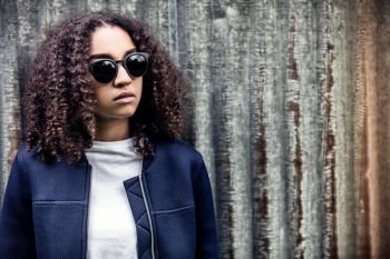 Beautiful mixed race African American girl teenager female young woman outside wearing sunglasses looking sad depressed or thoughtful