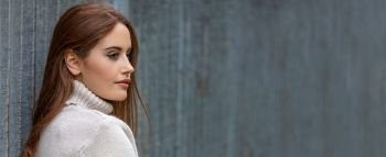 Panoramic banner image outdoor portrait of beautiful girl or young woman looking thoughtful with red hair wearing a white jumper 
