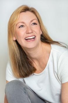 Studio portrait headshot of attractive happy middle aged blond woman in her forties