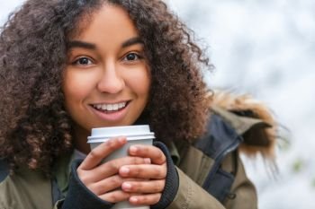 Beautiful happy mixed race African American girl teenager female young woman smiling drinking takeaway coffee outside 