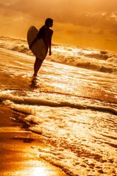 Stylized saturated rear view of beautiful sexy young woman surfer girl in bikini with white surfboard on a beach at sunset or sunrise