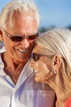 Happy senior loving man and woman romantic couple together outside in sunshine laughing wearing sunglasses