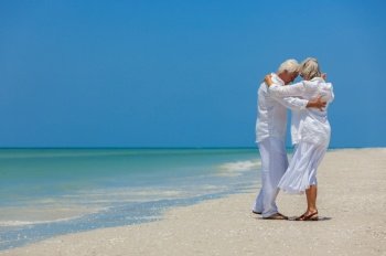 Happy senior man and woman retired couple on vacation dancing on a deserted tropical beach with bright clear blue sky