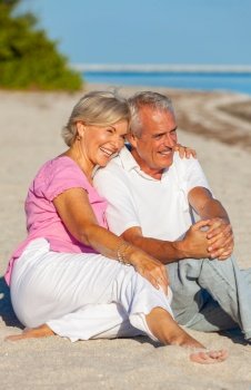 Happy retired, senior man and woman couple sitting, embracing, smiling and laughing on a sunny beach 