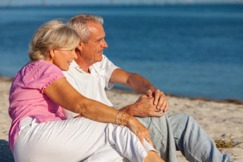 Happy senior man and woman retired couple sitting, smiling on a sunny beach 