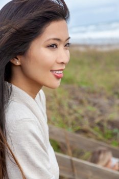 Outdoor portrait of a beautiful Chinese Asian young woman or girl with perfect white teeth