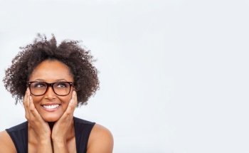 Beautiful intelligent mixed race African American girl or young woman smiling with perfect teeth, wearing glasses and looking up into white copy space