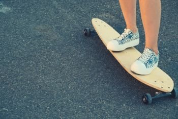 Young Girl legs standing on longboard closeup and a lot of copyspace. Girls legs standing on longboard closeup and a lot of copyspace