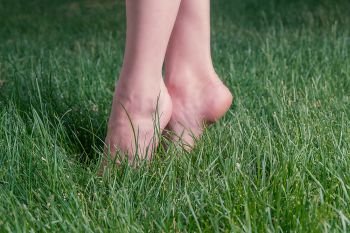 Barefoot Girl standing in green grass on toes backlit, harmony and carefree concept, copyspace. Girl standing in green grass on toes backlit, harmony and carefree concept