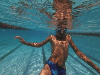 Boy swimming underwater in swimming pool in goggles. Boy swimming underwater in goggles