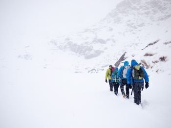Mountaineers team walks in fresh snow during a winter expedition. West italian Alps, Europe.