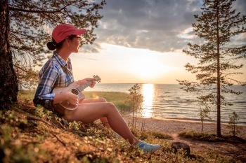 Woman at sunset playing the ukulele