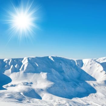 White winter mountains with snow and bright shining sun and sunrays
