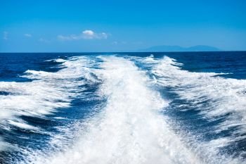 Wake of cruise boat on water surface and horizon with blue sea
