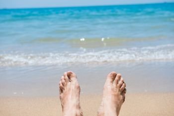 Closeup view of bare human feet on sand beach background. Summer vacation concept