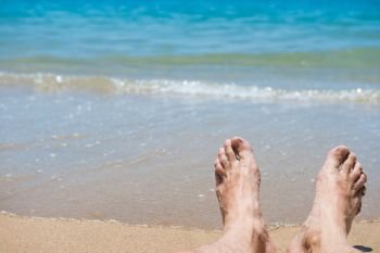 Closeup view of bare human feet on sand beach background. Summer vacation concept