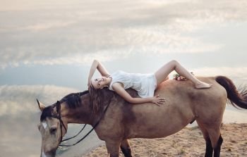 Portrait of a blond beautiful woman lying on the horse