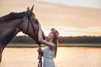 Pretty blond girl stroking a majestic horse