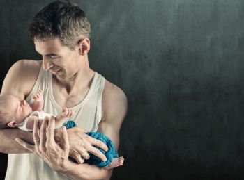 Father holding newborn son, over dark background