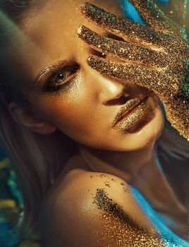 Beautiful lady with glittering golden hands and lips
