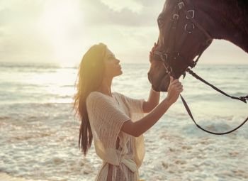 Charming woman stroking her beloved horse friend