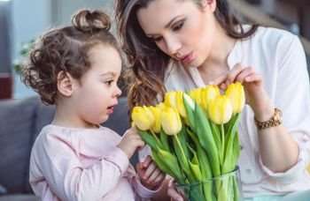 Beautiful mother showing tulips to her little daughter