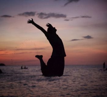 Silhouette of a relaxed, young man jumping on the beach