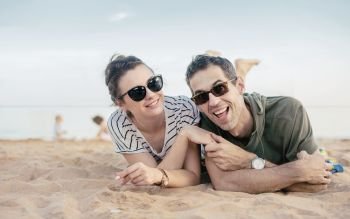 Portrait of a cheerful, relaxed couple laying on warm sand