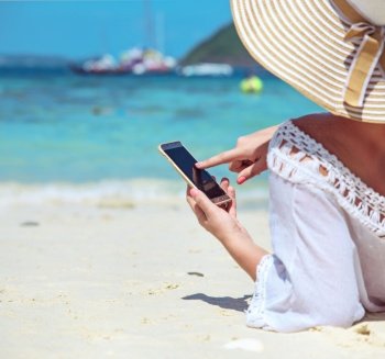 Relaxed woman using a smartphone on a tropical beach