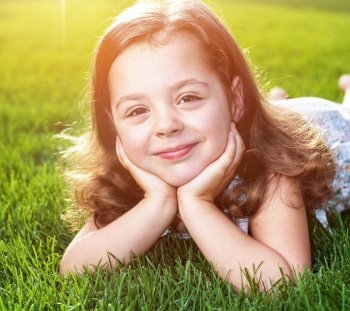 Closeup portrait of a cute little child lying on a fresh lawn