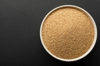 amaranth seeds in ceramic bowl isolated on dark background. top view