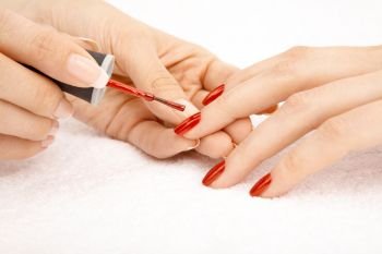 Process of drawing red varnish on the female nails, isolated