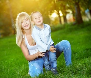 Young mum with the small son are amused in a summer garden