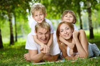 Happy family with two sons frolic on a lawn