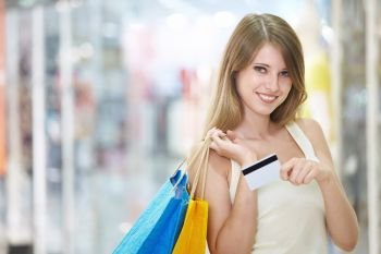 Young attractive girl with shopping and credit card in store